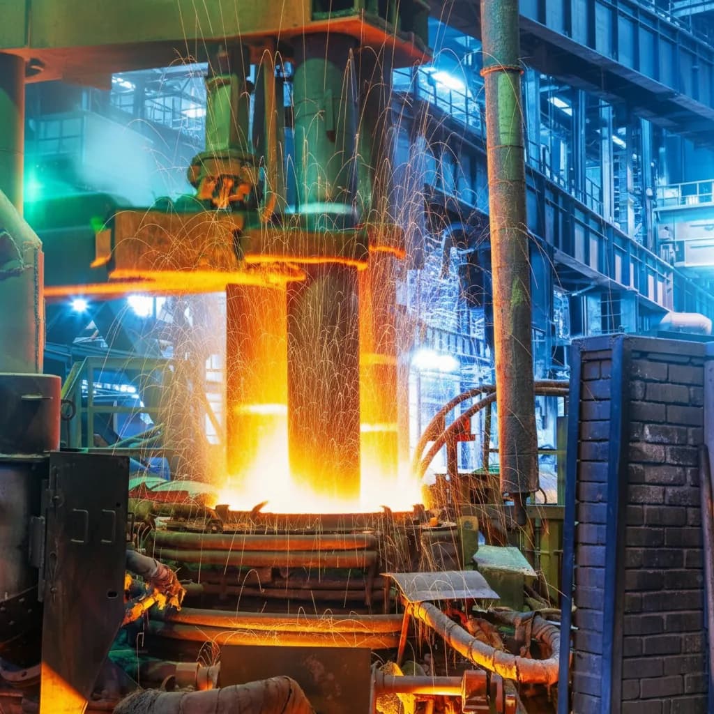 Horno eléctrico de una acería con electrodos de grafito y acero fundido incandescente lanzando chispas dentro de la nave industrial